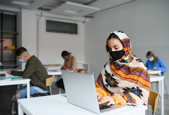 Study Overseas After Pandemic - Islamic student with face mask and laptop at desks at university
